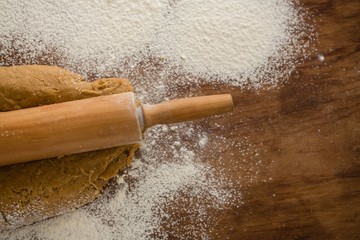 Flattening dough with rolling pin with sprinkled over flour on a