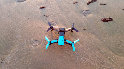 black and blue drone standing on the sand, view from above