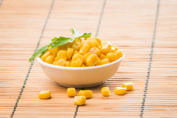 cooked sweet corn seeds in a  bowl on a wooden table. canned corn