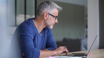 Middle-aged man working from home-office on laptop - Powered by Adobe