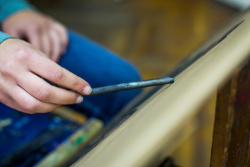 Young female artist painting with charcoal on paper