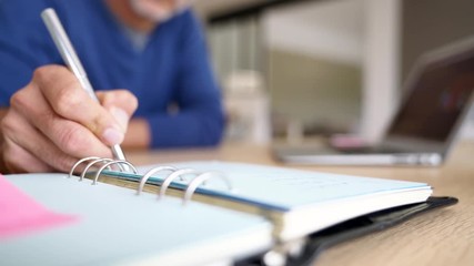 Closeup of man writing in agenda