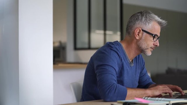 Middle-aged man working from home-office on laptop
