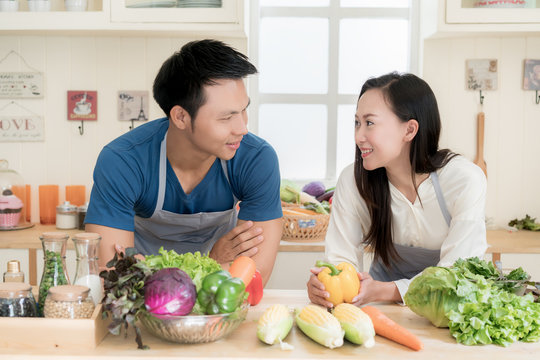 Young Asian couple preparing food together at counter in kitchen. Happy love couple concept.