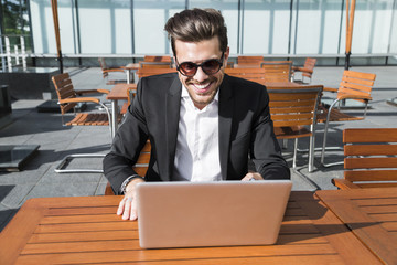 Male businessman or worker in black suit at the table and working on computer.