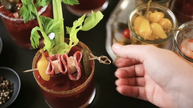 Bloody mary cocktail garnished with celery sticks, olives, and bacon strips