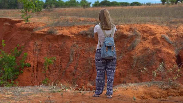 Red haired woman shoots photos in a red canyon in a desrt in Mui Ne, Vietnam