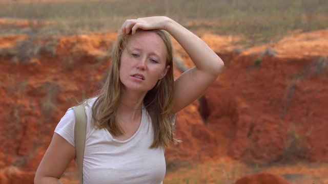 Red haired woman shoots photos in a red canyon in a desrt in Mui Ne, Vietnam