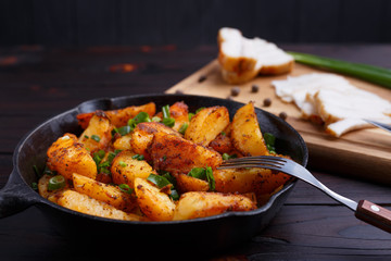Appetizing countryside homemade meals. Delicious roasted potatoes, bacon and scallion on dark wooden table. Home food close up