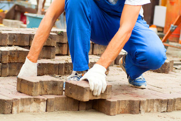 Laying Paving Slabs by mosaic close-up. Repairing sidewalk. Workers laying stone paving slab. laying of paving slabs by a professional master builder in blue overalls