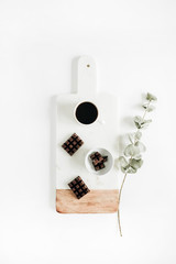 Coffee and chocolate on vintage marble cutting board with eucalyptus branch. Flat lay, top view food concept.