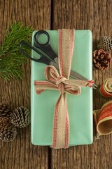Scissors, pine cones, leaves and ribbon with wrapped gift box on