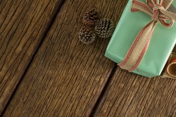 Pine cones and wrapped gift box on wooden table