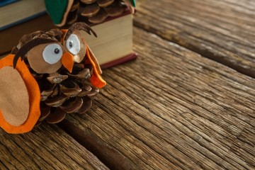 Owl decorated with pine cone and book stack on wooden table