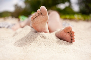 close up of beautiful young woman feet taking sun bath on the beach