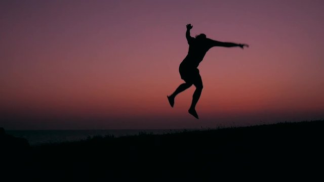Silhouette of Young Happy Man Running and Jumping at Beautiful Pink Sunset. HD Slowmotion Carefree Lifestyle Freedom Footage.