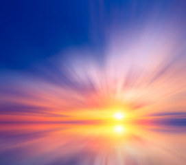 Obraz premium Morski zachód słońca z jasnym słońcem i kolorowymi chmurami.