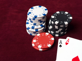 Pair of aces in a poker game. Poker chips, cards and red cloth. The concept of luck in the game.