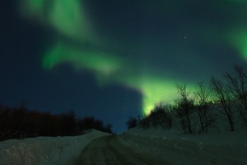 Fototapeta na wymiar Aurora,Northern lights over the hills and road.