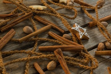 Close up of rope with star shape cookies and cinnamon sticks by