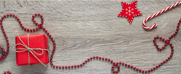 Red gift box wiyh Christmas decorations on wooden background. Space for text.