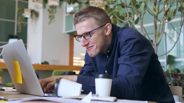 Funny Crazy Programmer with Caffeine Addiction Drinking Coffee and Typing Fast on Laptop in the Office. 4K.