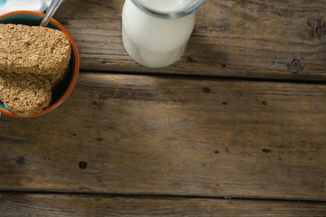 Granola bar and milk on wooden table