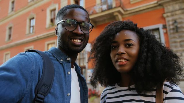 Happy young attractive African couple in love taking selfie on street of ancient town in weekend. Couple smiling. Outdoors.