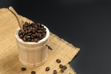 Fototapeta na wymiar A cup of coffee and coffee bean grain on sack fabric put on black wood table background include copyspace for add text or graphic