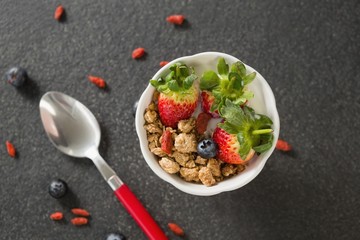 Bowl of breakfast cereals and fruits with spoon