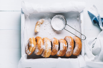 Homemade donuts with powdered sugar in a white wooden box