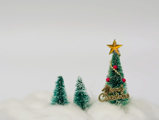 Artificial Christmas trees decorated with star, ornament and Christmas text with snow background using for Christmas decoration concept.
