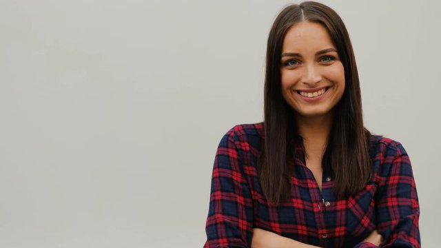 Portrait of beautiful young woman wearing checkered shirt standing on white background. Girl looking stylish. Outdoors.