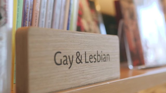 Young Woman Taking Book from Shelf in the Library or Shop. Concept of Sexual Education and Choice. 4K, Slow Motion.