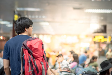 Young Asian man traveler carrying red backpack in airport terminal, travel lifestyle in transportation building concept