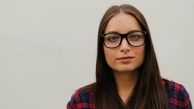 Portrait of attractive young woman in glasses with closed eyes wearing checkered shirt on white background. Close-up.