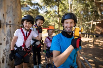 Obraz premium Kids and instructor getting ready to zip line in park