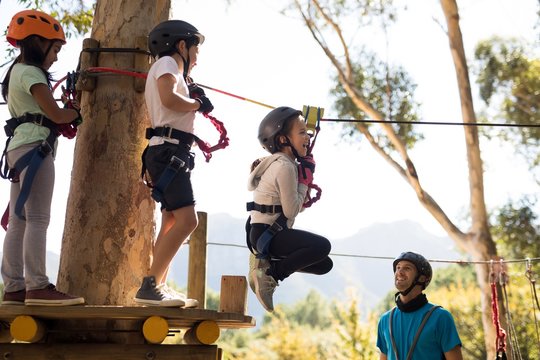 Kids Enjoying Zip Line Adventure On Sunny Day