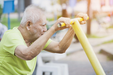 side view of seniors doing exercise Arms and legs with using cycling exercise bikes on park. elderly man or people retired relaxing in park. retired,health and lifestyle concept