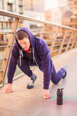 The young sporty man standing in pose for start to run outdoors