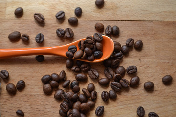 Coffee beans at orange spoon at wooden table/ top view/ still life food photography