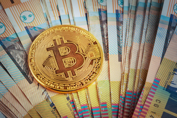 Golden bitcoin glowing on pile of Australian 50 dollar banknotes
