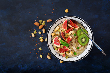 Delicious and healthy oatmeal with figs, nuts, kiwi and seeds. Healthy breakfast. Fitness food. Proper nutrition. Flat lay. Top view.