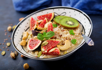 Delicious and healthy oatmeal with figs, nuts, kiwi and seeds. Healthy breakfast. Fitness food. Proper nutrition.