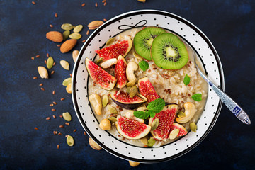 Delicious and healthy oatmeal with figs, nuts, kiwi and seeds. Healthy breakfast. Fitness food. Proper nutrition. Flat lay. Top view.