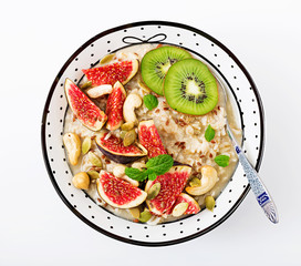 Delicious and healthy oatmeal with figs, nuts, kiwi and seeds isolated on white background. Healthy breakfast. Fitness food. Proper nutrition.
