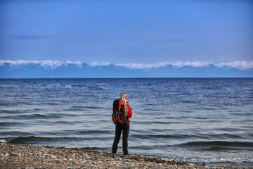 Traveler wearing in warm clothing with backpack enjoying view of sea