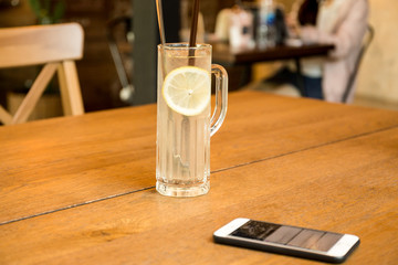 Health care fresh lemon juice drink with cell phone on wooden table