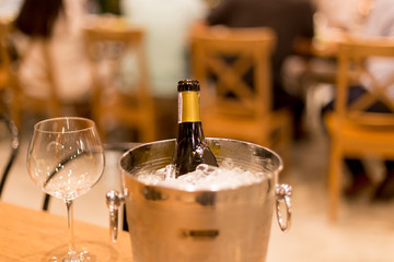 Shot in high iso with low light wine bottle in bucket with ice and wine glasses on table