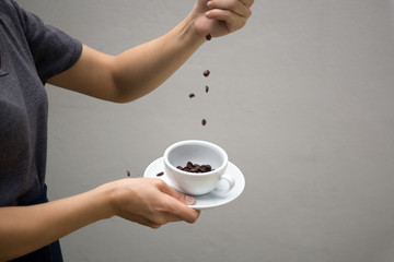 Woman drop fresh roasted coffee beans into a cup